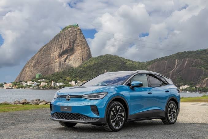 SUV elétrico azul estacionado diante de um morro à beira da baía